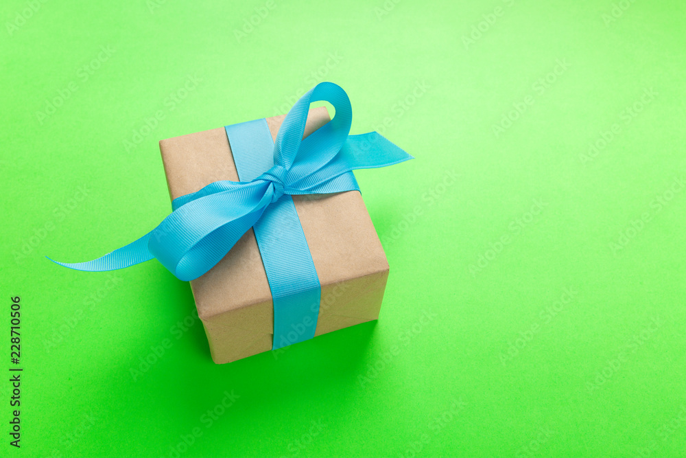 gift wrapped and decorated with blue bow on green background with copy space. Flat lay, top view gift wrapped and decorated with blue bow on green background with copy space. Flat lay, top view