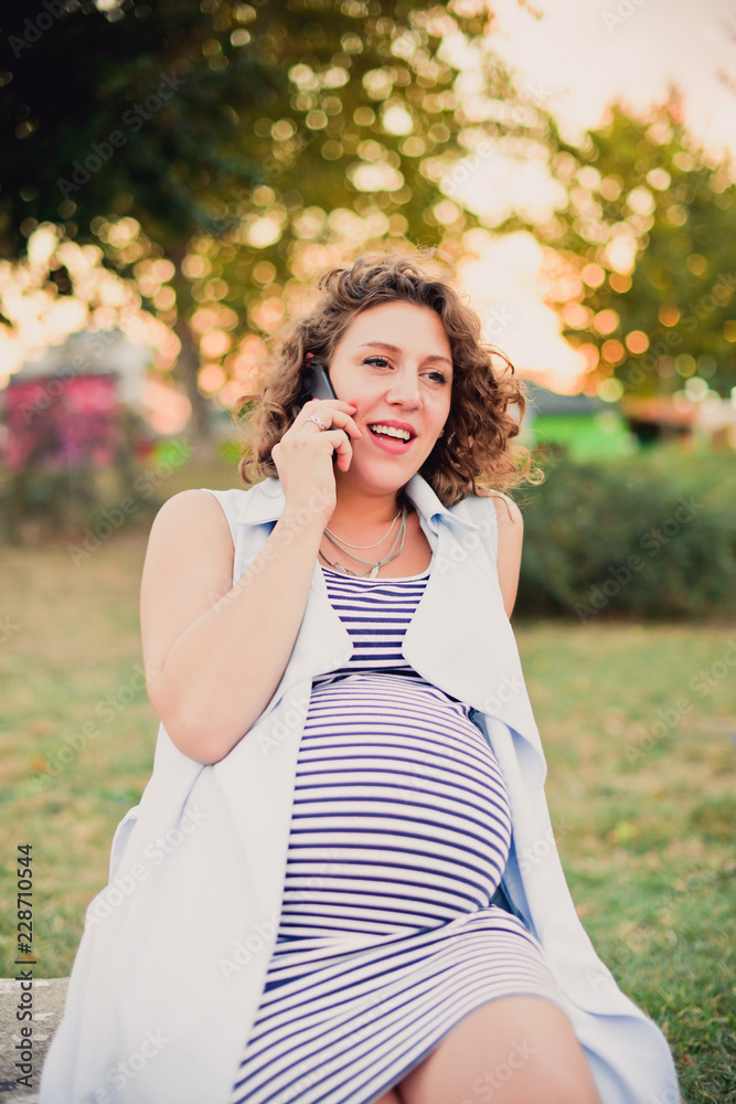 Pregnant woman talking on the phone outdoors Pregnant woman talking on the phone outdoors