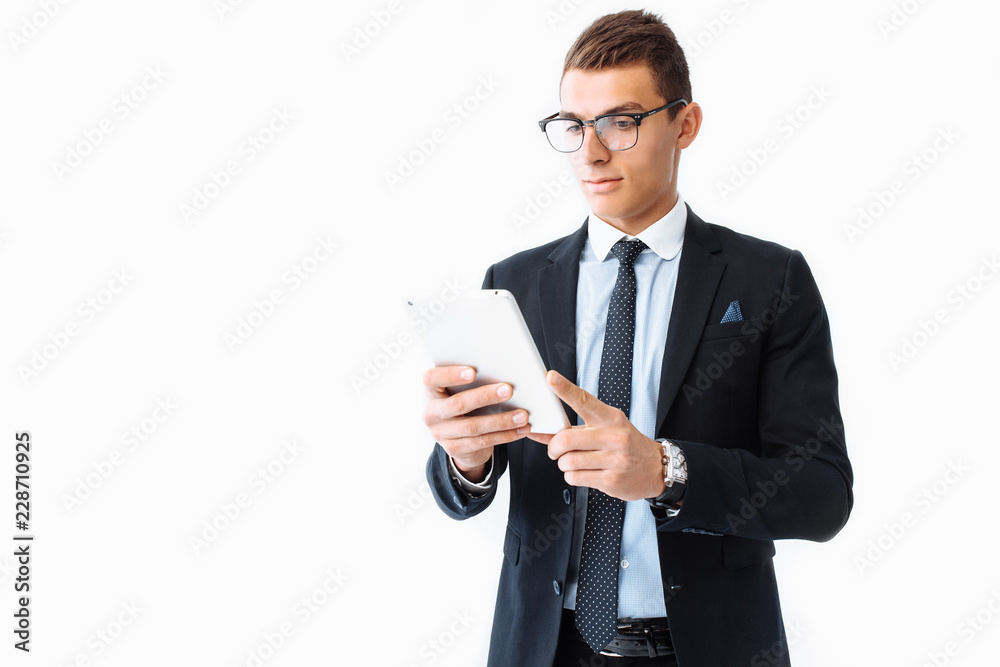 Business man, in a suit and glasses, working on a digital tablet, standing on a white background