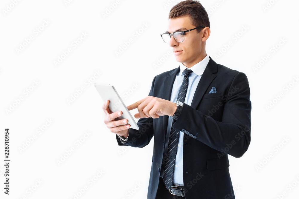 Business man, in a suit and glasses, working on a digital tablet, standing on a white background Business man, in a suit and glasses, working on a digital tablet, standing on a white background