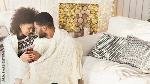 Loving african-american couple drinking mulled-wine in cozy room