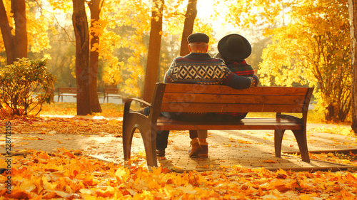 Senior couple enjoying sunset on the bench in the autumn park