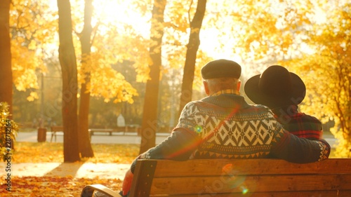 Senior couple enjoying sunset on the bench in the autumn park