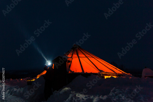 Norway. Photographer Dave Stevenson wearing head torch outside traditional Norwegian lavvu tent.
