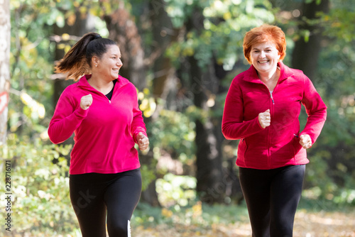 Mother and daughter wearing sportswear and running in forest