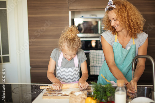 Quadro su tela Little Chef with the help of Mom preparing dough and ingredients of pizza, at th