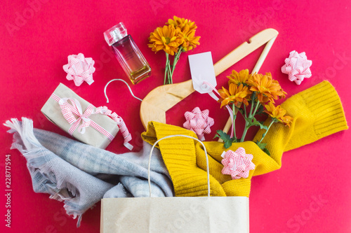 Paper craft package with women's purchases - clothes, gifts, perfumes, flowers and hangers. On a bright red background. Black friday concept. Top view, flat lay