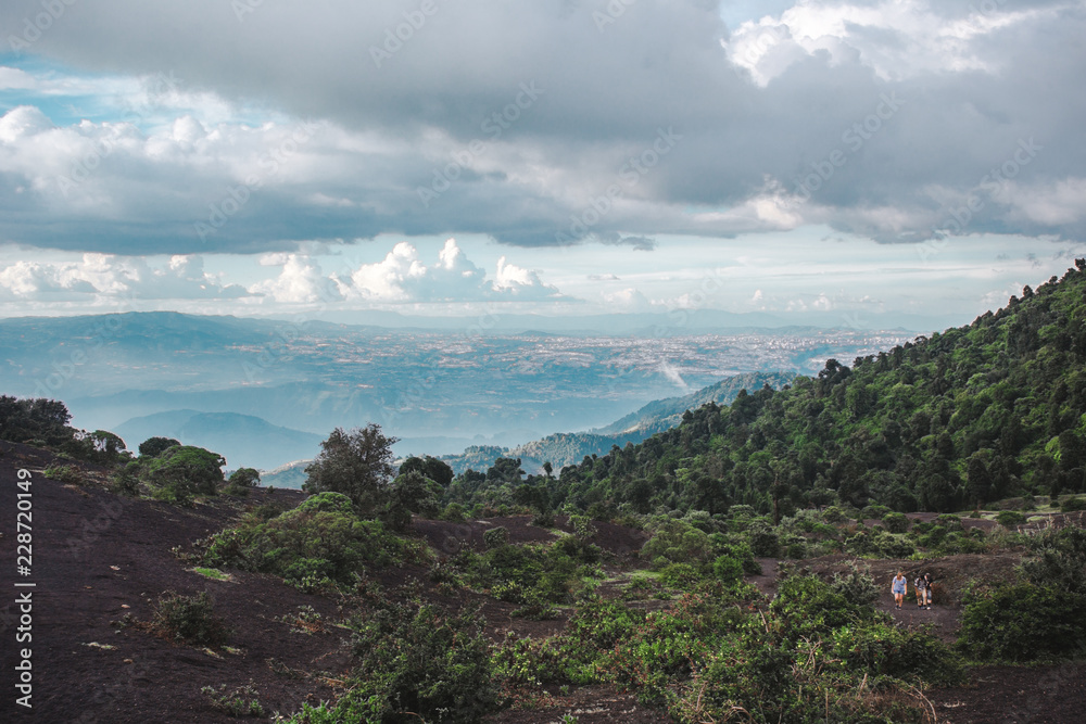 Fototapeta premium Tourists hike thehanging landscapes around the Volcan Pacaya, one of Guatemala's most active volcanoes, from black volcanic rock to lush green forests