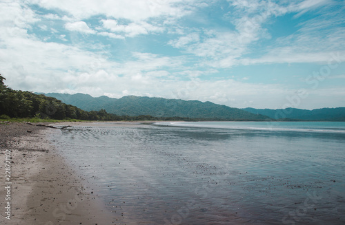 Tide out on the empty Bahia Ballena with no people on a sunny day near Montezuma, on the Pacific coast of Costa Rica