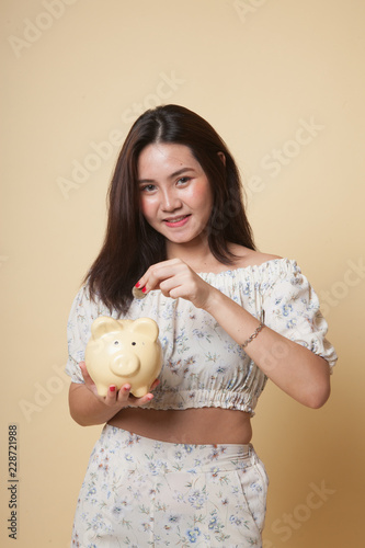 Asian woman with coin and pig coin bank.