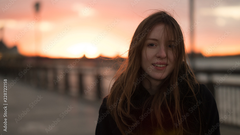 Sunset portrait of beautiful girl. Winded, Blur background.