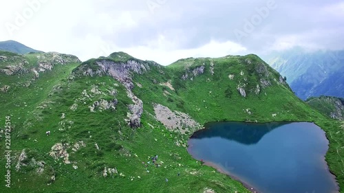 Aerial view of emerald lake high in the mountains in Abkhazia overlooking the mountains and ravines and running clouds photo