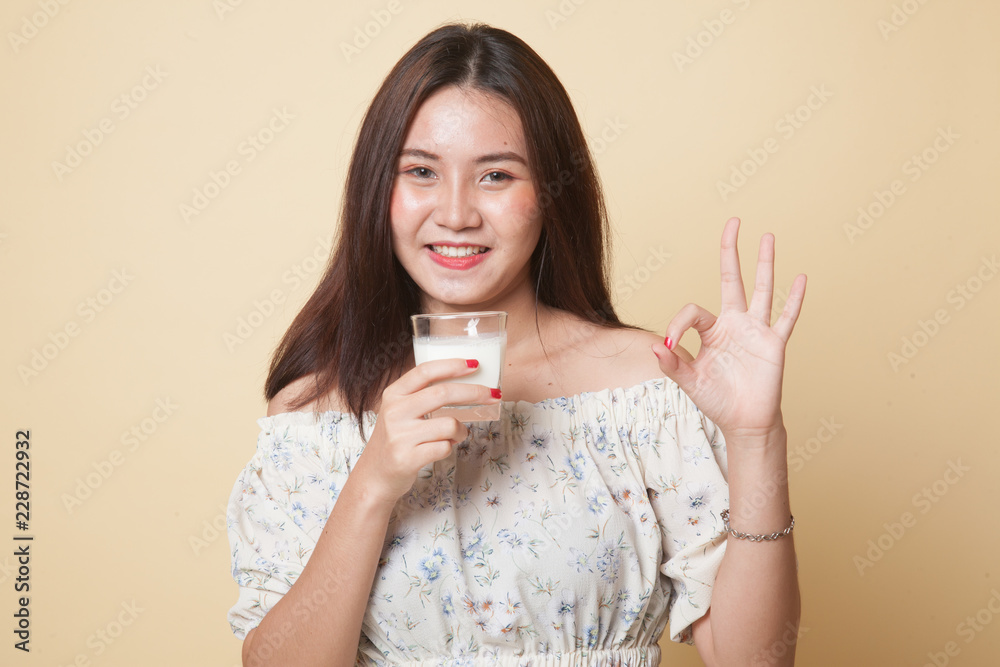 Healthy Asian woman drinking a glass of milk show OK sign. Healthy Asian woman drinking a glass of milk show OK sign.