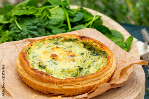 Close-up of quiche with fresh vegetables. Background in green tones. Rustic and country aspect.