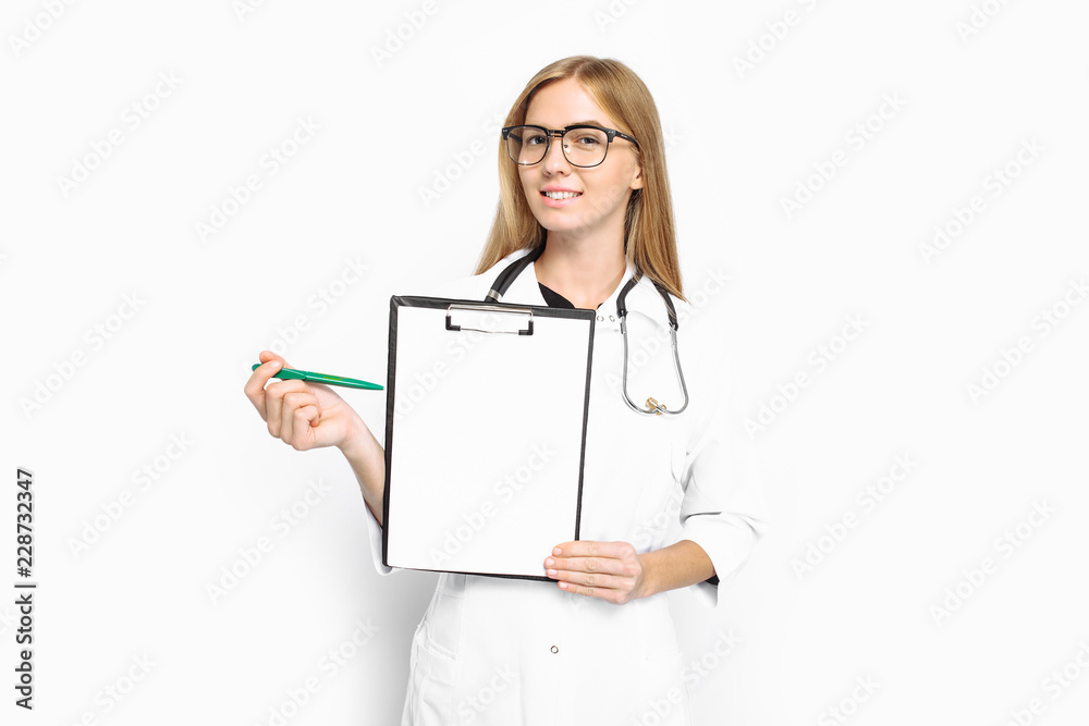 Young female doctor in glasses and a stethoscope, showing a file with an empty sheet of paper, on a white background. Young female doctor in glasses and a stethoscope, showing a file with an empty sheet of paper, on a white background.