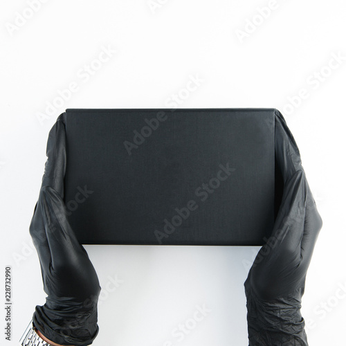 Hands of the girl with the black box. Blogger Flatley holds the mask. White background and a minimalist cut. © pavelvozmischev