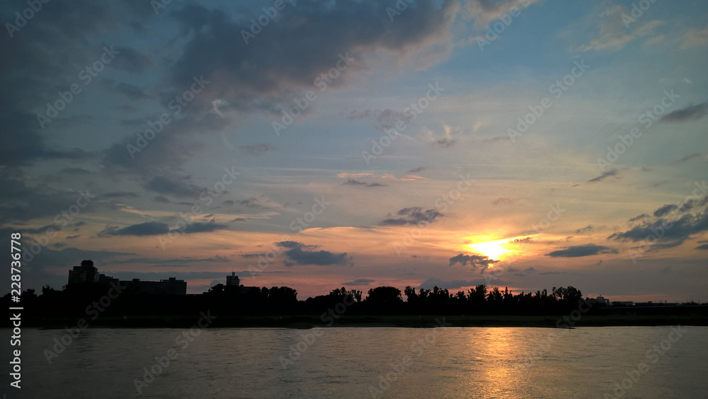 Sonnenuntergang am Flussufer mit Sonnenstrahlen im Himmel