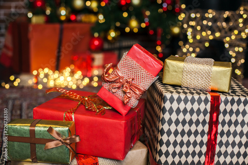 Close up Christmas gift box. Christmas presents in red and brown boxes on Christmas Tree background in loft interior copy space. photo