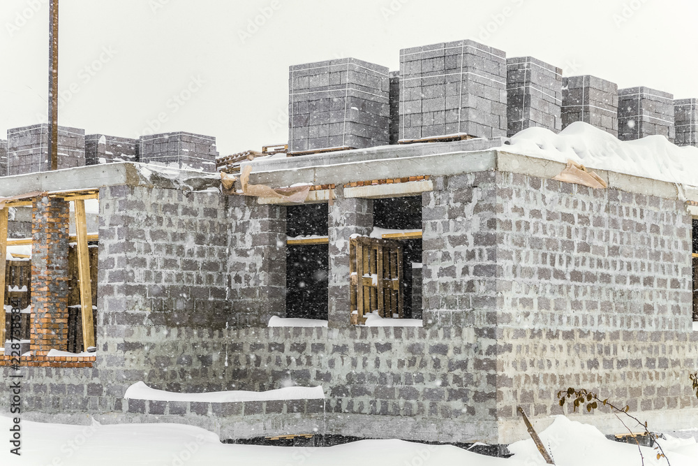 Construction of a country house stopped for the winter. Snow-covered suburban construction site.