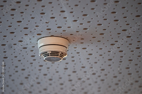 Rauchmelder einer Brandmeldeanlage an einer Akustikdecke in einem öffentlichen Gebäude