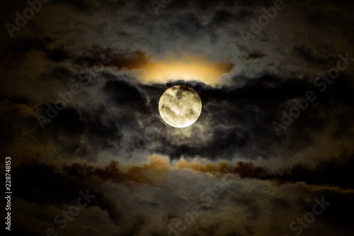Full moon ascending behind dark clouds