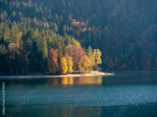 Image of a lake and colorful trees with people on the shore photo