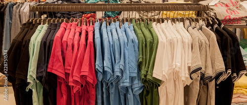 Colorful t-shirts on hangers. Men s stylish clothes. Showcase  sale  shopping. Fashion and trade concept