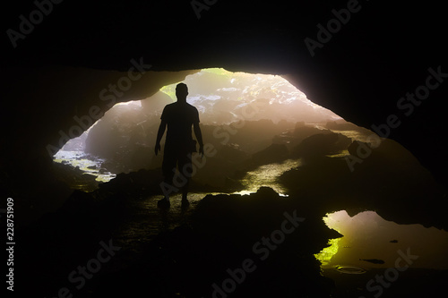 Silhouette of Figure in Dark Foggy Cave with River photo