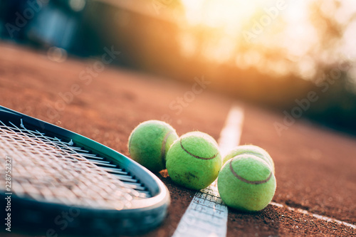 Balls and tennis racket on clay court. © kojala