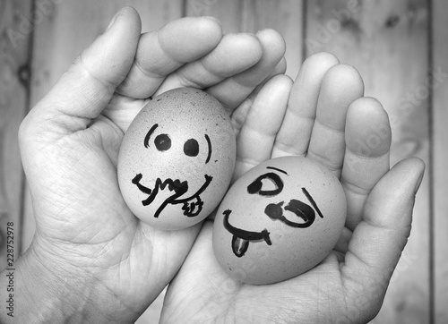 An egg staring lustfully, lecherously at another egg, both in female hands. Two eggs in love, being together, Eggs faces, drawnigs on eggs.  photo