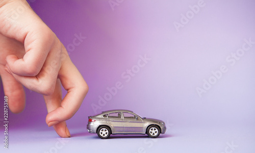 Toy child car in woman's hand. Purchase insurance bank loan travel where to go trip journey concept. Isolated on violet