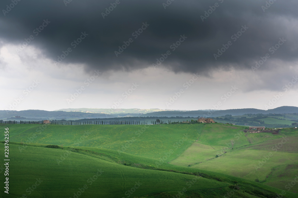 Dramatic view of green fields and meadows at sunset in Tuscany