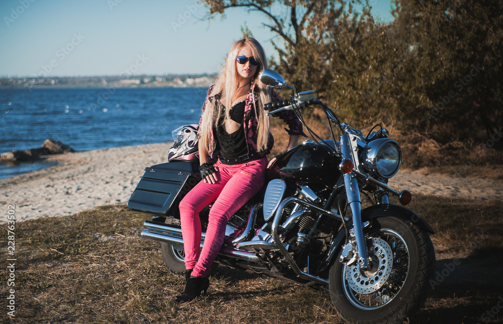 Beautiful woman posing on motorcycle outdoor.
