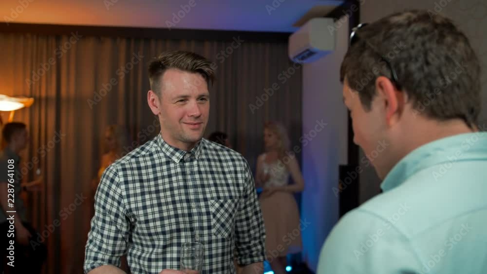 Young handsome guy drinking champagne and talking with his friend at private flat party. Young handsome guy drinking champagne and talking with his friend at private flat party.