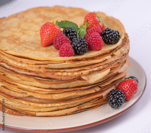 Стопка блинов на тарелке с фруктами
