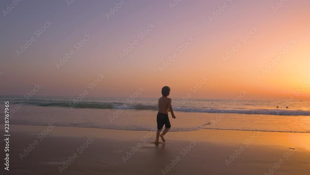 Silhouette of child running and playing in the beach at sunset - freedom Silhouette of child running and playing in the beach at sunset - freedom
