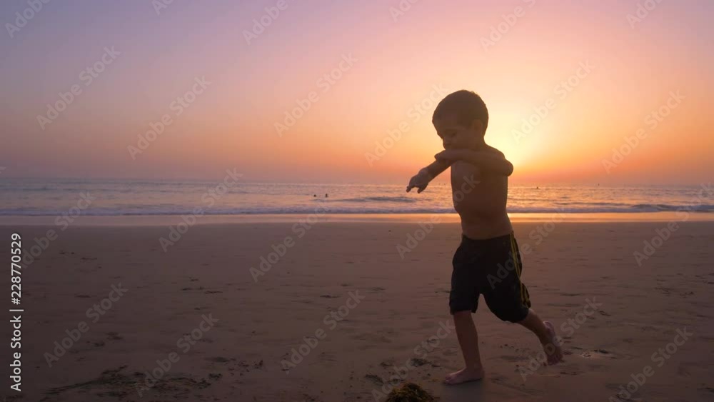 Silhouette of child running and playing in the beach at sunset - freedom Silhouette of child running and playing in the beach at sunset - freedom
