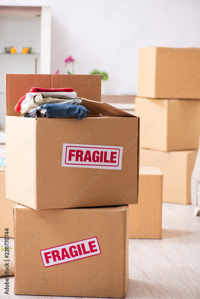 Fototapeta premium Young couple moving to new flat with fragile things