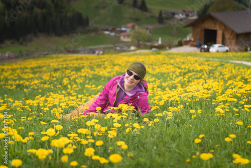 Active healthy woman having rest on beautiful meadow covered with flowers. Portrait of happy smiling young woman resting of mountains clearing during hike holidays