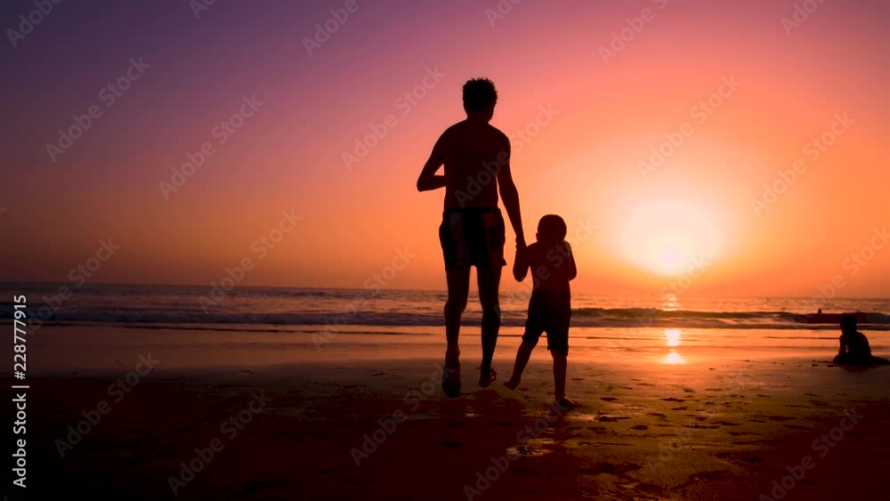 Silhouette of father with two children in the beach at sunset Silhouette of father with two children in the beach at sunset