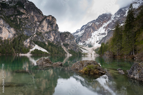 Magnificent lake Lago di Braies. The emerald smooth surface of water reflects the wood and mountains around. Walk to South Tyrol, Italy. The concept of walking and eco-tourism