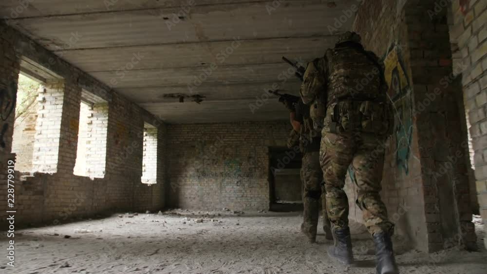 Rear view of special forces in camouflage with weapons running in abandoned building during military operation. Squad of marines storming enemy building using special equipment and tactical devices. Rear view of special forces in camouflage with weapons running in abandoned building during military operation. Squad of marines storming enemy building using special equipment and tactical devices.