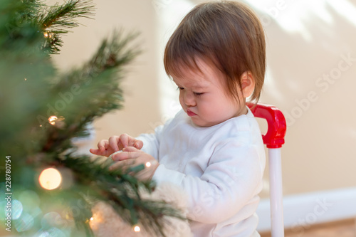Toddler boy decorating the Christmas tree in his house