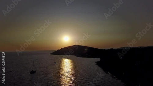 Aerial footage of sunset. Sun going down behind island. Sailing boats in bay waiting evening. photo