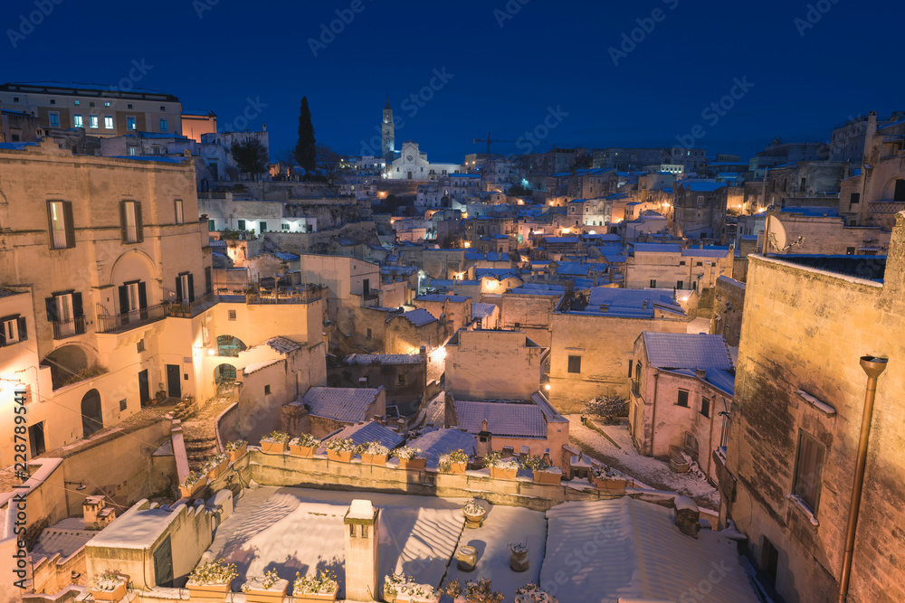 Night shot of Matera, Basilicata, Italy: picturesque ancient streets in the old town called Sassi di Matera in snow, winter