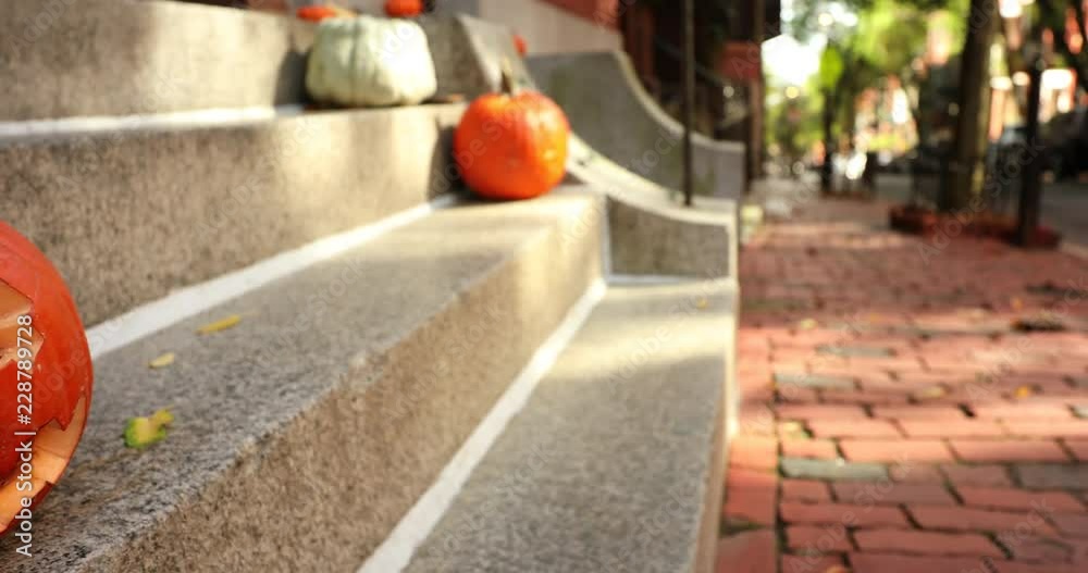 A scary carved pumpkin Jack o Lantern on the steps of a home before Halloween trick or treat