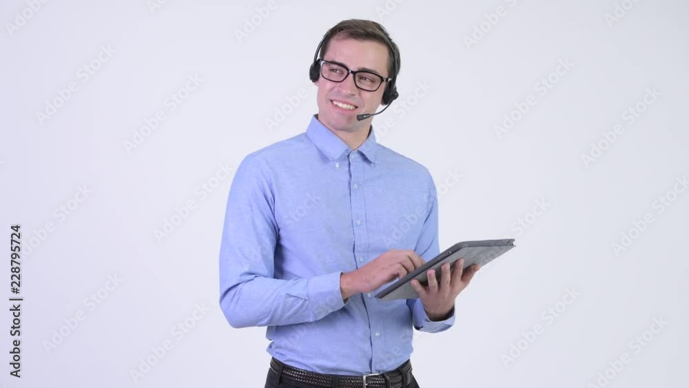 Young happy handsome businessman as call center representative thinking while using digital tablet