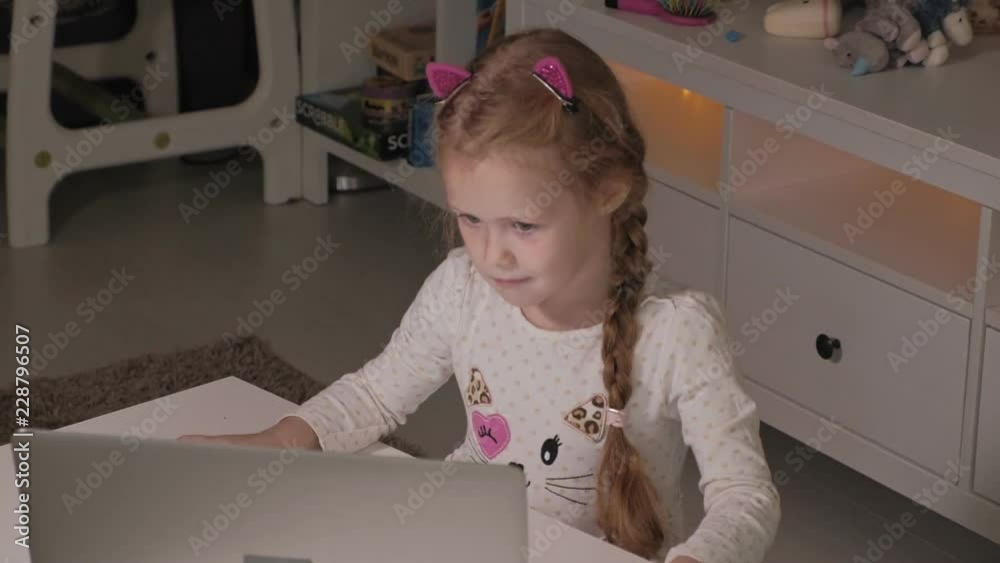 Happy little girl at home working with a laptop Happy little girl at home working with a laptop
