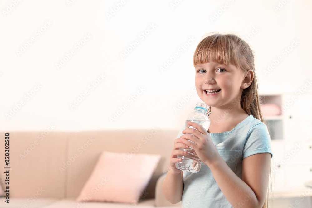 Cute little girl holding bottle with water at home. Space for text Cute little girl holding bottle with water at home. Space for text