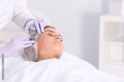 Woman undergoing face biorevitalization procedure in salon. Cosmetic treatment